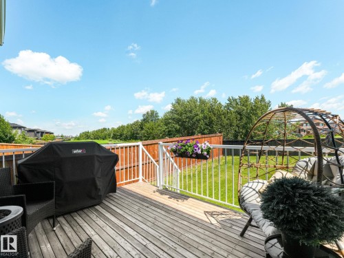 Spacious wood-finish deck with white railings overlooking a green lawn - 5411 66 Street, Beaumont, AB 