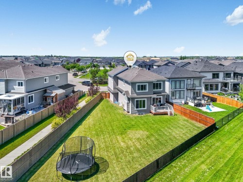 Spacious rear yard with a manicured lawn, wood fencing, and a black chain-link fence - 5411 66 Street, Beaumont, AB 