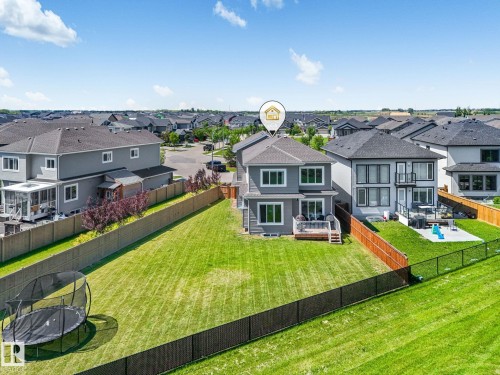 Expansive backyard featuring a large green lawn, two-story exterior, and a ground-level wood deck - 5411 66 Street, Beaumont, AB 