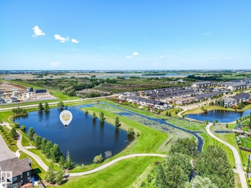 Expansive neighborhood featuring multiple ponds, paved walking paths, established residential structures, open green spaces, and distant undeveloped land - 5411 66 Street, Beaumont, AB 