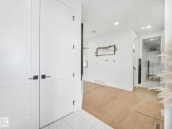 Entryway featuring white panel doors with matte black hardware, tile flooring, and light wood-finish flooring extending into the interior - 