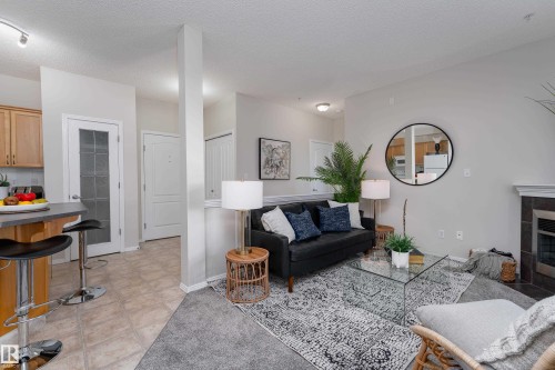 Living area featuring a fireplace with dark tile surround, light gray wall paint, and recessed lighting - 404 12111 51 Avenue, Edmonton, AB 