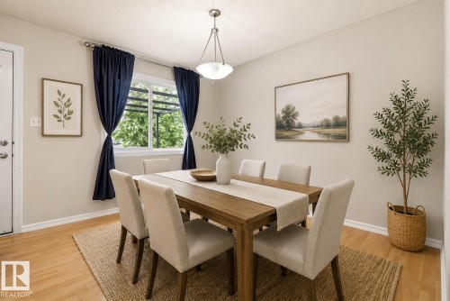 Dining area featuring wood-finish flooring, a white trim baseboard, and a double-hung window - 2369 27 Avenue, Edmonton, AB 
