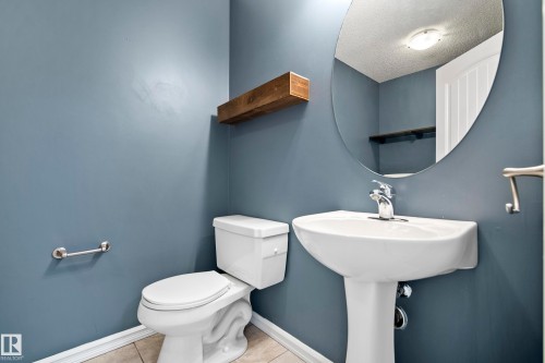 Pedestal sink with chrome faucet, complemented by a large oval mirror - 2369 27 Avenue, Edmonton, AB 