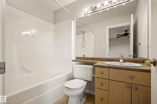 Bathroom featuring a full vanity with an integrated sink, a large wall-mounted mirror, and a tub/shower combination with white surround - 2369 27 Avenue, Edmonton, AB 