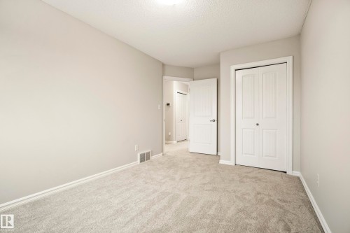 Neutral-toned walls and plush gray carpeting characterize this bright interior space, featuring white baseboards and trim - 2369 27 Avenue, Edmonton, AB 
