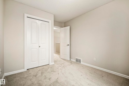 Carpeted room with light grey walls, white trim, and a white bi-fold closet door - 2369 27 Avenue, Edmonton, AB 
