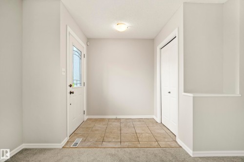 Entryway featuring ceramic tile flooring, a decorative glass-paneled entry door, a flush-mount ceiling light fixture, and a built-in closet with bi-fold doors - 2369 27 Avenue, Edmonton, AB 