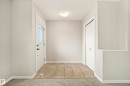 Entryway featuring ceramic tile flooring, a decorative glass-paneled entry door, a flush-mount ceiling light fixture, and a built-in closet with bi-fold doors - 2369 27 Avenue, Edmonton, AB 
