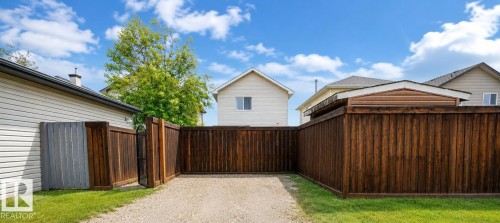 Gravel driveway featuring a privacy fence, secure gate, and manicured lawn - 2369 27 Avenue, Edmonton, AB 