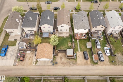 Rear exterior featuring a spacious concrete patio, a wooden deck, and a detached two-car garage - 2369 27 Avenue, Edmonton, AB 