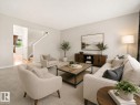 Spacious living area featuring light-toned carpeting, neutral wall finishes, and an open entryway to a staircase - 2369 27 Avenue, Edmonton, AB 