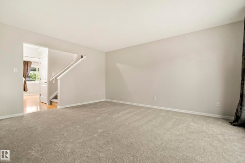 Spacious living area featuring light gray carpeting and neutral wall paint - 2369 27 Avenue, Edmonton, AB 