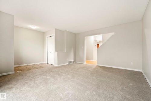 Open living area featuring light gray walls, white baseboards, and neutral carpeting - 2369 27 Avenue, Edmonton, AB 