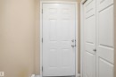 Panel-style entry door with chrome hardware, complemented by light beige wall paint and white trim - 95 3040 Spence Wynd, Edmonton, AB 