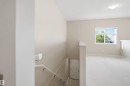 Carpeted upper level with a prominent window, flush-mount lighting, and a white interior door - 95 3040 Spence Wynd, Edmonton, AB 