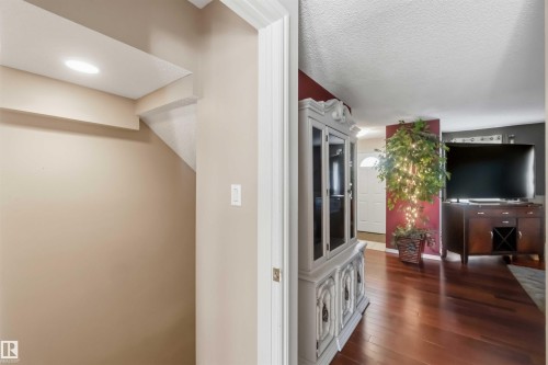 Recessed lighting illuminates a neutral-toned wall with a white trim doorway leading to a space with wood-finish flooring - 14121 23 Street, Edmonton, AB 