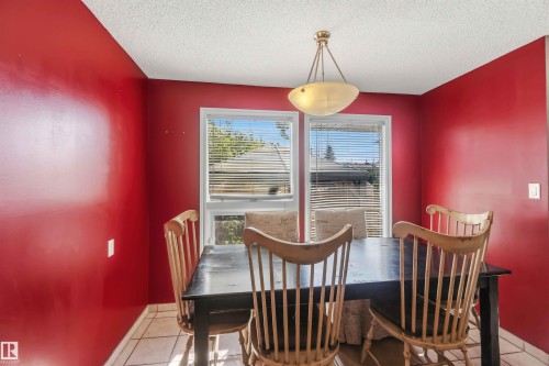Dining area featuring bold red walls, white trim, and a textured ceiling - 14121 23 Street, Edmonton, AB 