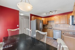 Kitchen featuring wood cabinetry, stainless steel refrigerator and dishwasher, tile flooring, and a tile backsplash - 