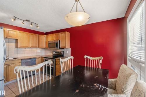 Kitchen and dining area featuring red accent wall - 14121 23 Street, Edmonton, AB 