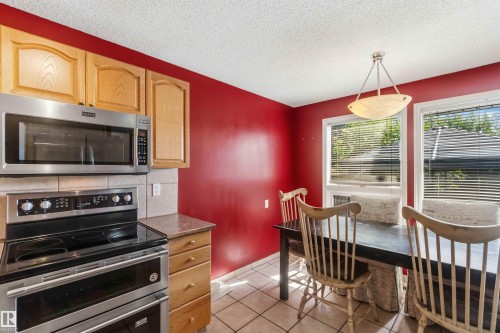 Kitchen area featuring wood cabinetry, stainless steel microwave, and an electric range with a double oven - 14121 23 Street, Edmonton, AB 