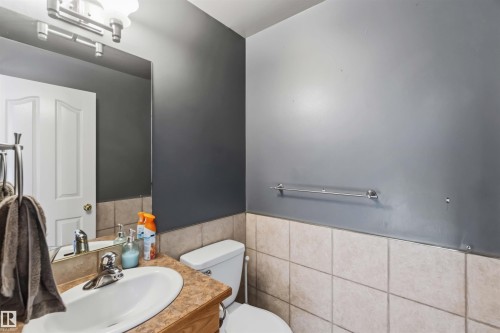 Bathroom featuring a single vanity with an oval basin, a laminate countertop, and wood-finish cabinetry - 14121 23 Street, Edmonton, AB 