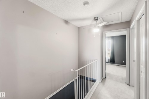 Second-level hallway featuring light gray walls, white railing, and a modern ceiling fan with integrated lighting - 14121 23 Street, Edmonton, AB 