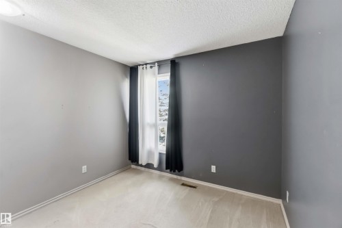 Spacious interior room featuring light-colored carpet flooring and a window with a white frame - 14121 23 Street, Edmonton, AB 