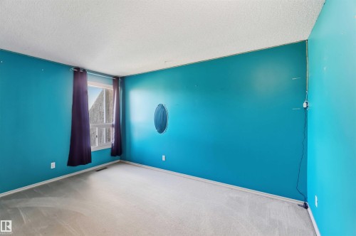 Interior room featuring light-colored carpeting and vibrant blue wall paint - 14121 23 Street, Edmonton, AB 