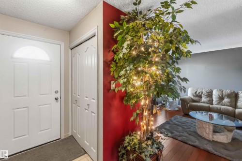 Entryway featuring a white paneled door with an arched transom window, bi-fold closet doors, and wood-finish flooring - 14121 23 Street, Edmonton, AB 