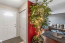 Entryway featuring a white paneled door with an arched transom window, bi-fold closet doors, and wood-finish flooring - 14121 23 Street, Edmonton, AB 