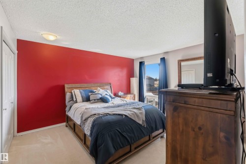 Bright bedroom with a red accent wall and neutral carpeting - 14121 23 Street, Edmonton, AB 