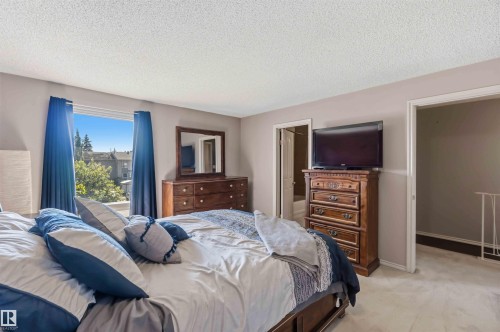 Spacious bedroom featuring light-colored walls, carpeted flooring, and a large window - 14121 23 Street, Edmonton, AB 