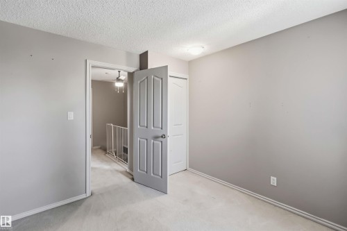 Carpeted room featuring a ceiling-mounted light fixture, light gray wall paint, and white trim - 14121 23 Street, Edmonton, AB 