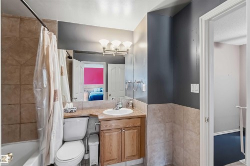 Bathroom featuring a vanity with wood-finish cabinetry, a white basin sink, and a light-toned countertop - 14121 23 Street, Edmonton, AB 