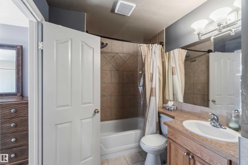 Full bathroom featuring a single vanity with an integrated sink, a large wall-mounted mirror, and an overhead vanity light fixture - 14121 23 Street, Edmonton, AB 