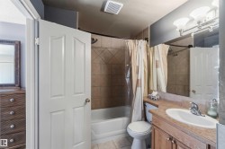 Full bathroom featuring a single vanity with an integrated sink, a large wall-mounted mirror, and an overhead vanity light fixture - 