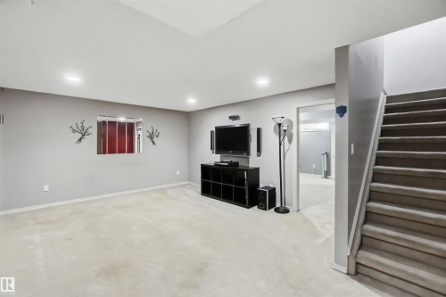 Carpeted recreation room with recessed lighting, a finished stairwell with carpeted treads, and a doorway leading to an additional finished space - 14121 23 Street, Edmonton, AB 