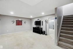 Carpeted recreation room with recessed lighting, a finished stairwell with carpeted treads, and a doorway leading to an additional finished space - 