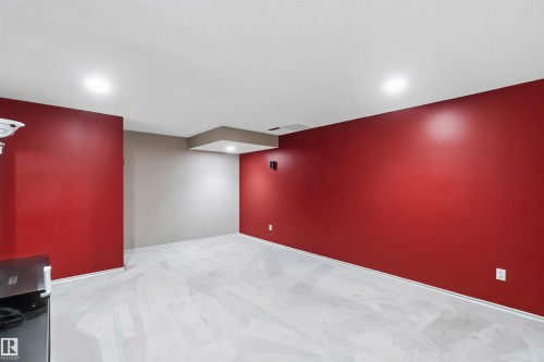 Spacious interior room featuring red and gray painted walls, recessed ceiling lighting, and light-colored flooring - 14121 23 Street, Edmonton, AB 