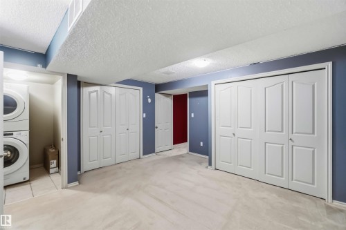 Room featuring white bi-fold doors, blue painted walls, and light-colored carpet flooring - 14121 23 Street, Edmonton, AB 