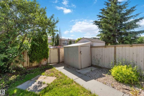 Compact storage shed with a sloped roof, concrete flooring, and surrounding gravel landscaping - 14121 23 Street, Edmonton, AB 