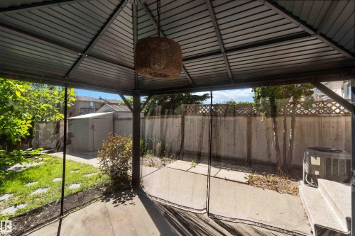 Metal-framed gazebo with a slatted roof, featuring a hanging woven fixture and transparent screens - 14121 23 Street, Edmonton, AB 