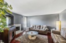 Living space featuring rich wood-finish flooring, a tiled fireplace, and neutral wall tones - 14121 23 Street, Edmonton, AB 
