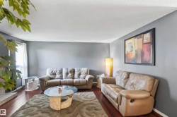 Spacious living area featuring rich wood-finish flooring and neutral wall tones - 