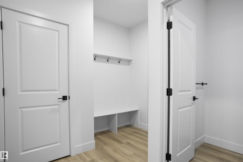 Mudroom featuring built-in bench storage, wall-mounted coat hooks, and wood-finish flooring - 1915 164 Street, Edmonton, AB 
