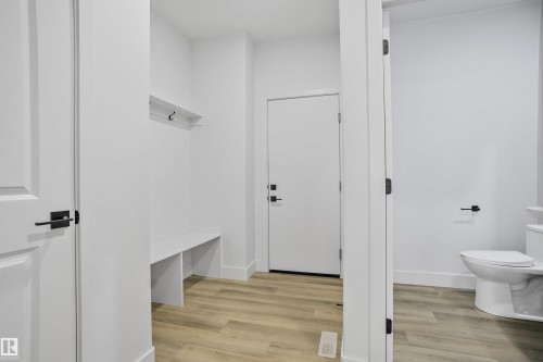 Entryway featuring wood-finish flooring, a built-in bench, and wall-mounted coat hooks - 1915 164 Street, Edmonton, AB 