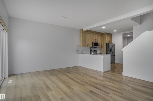 Open concept living area featuring wood-finish flooring and light gray walls - 1915 164 Street, Edmonton, AB 
