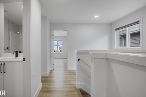 Upper-level hallway featuring wood-finish flooring, white walls, and recessed lighting - 1915 164 Street, Edmonton, AB 