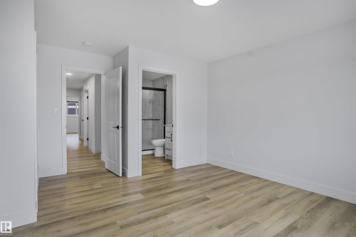 Spacious interior room featuring light wood-finish flooring, white walls, and bright overhead lighting - 1915 164 Street, Edmonton, AB 